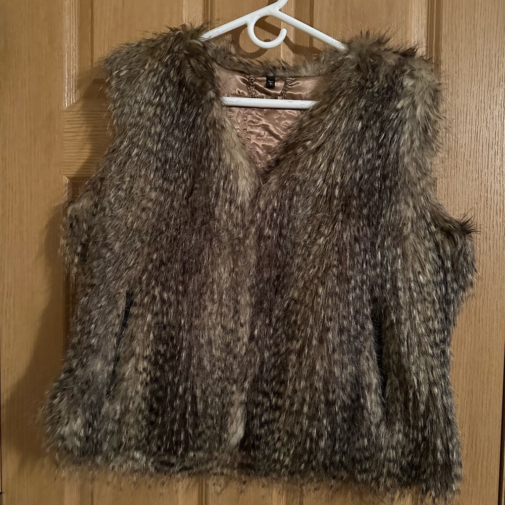 Faux Fur vest with closures. Side pockets trimmed in faux black leather